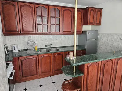 a kitchen with wooden cabinets and a sink at Lazur Family Apartment Pomorie in Pomorie