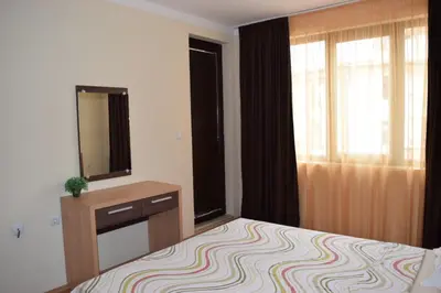 a bedroom with a bed and a dresser and a window at Sea Club Sarafovo Apartments in Burgas City