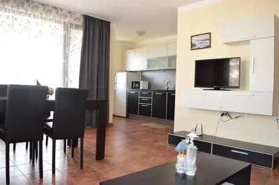 a living room with a dining table and a kitchen at Sea Club Sarafovo Apartments in Burgas City