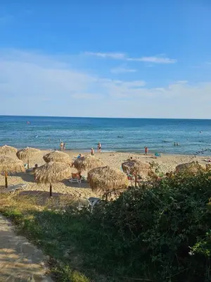 a beach with straw umbrellas and people on the beach at Meerblick , Etera 4 in Sunny Beach