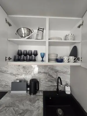 a kitchen with white shelves with dishes and a sink at Grand Villa Deluxe Apart in Sveti Vlas