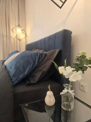 a black chair with pillows and a glass table with flowers at Grand Villa Deluxe Apart in Sveti Vlas