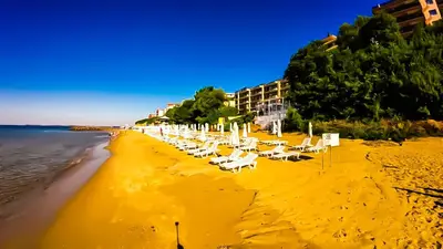 a beach with white lounge chairs and the ocean at William's apartments - cute studio in Sveti Vlas