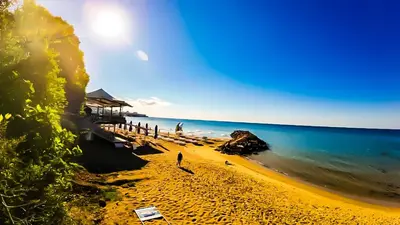 a beach with people standing on the sand and the ocean at William's apartments - cute studio in Sveti Vlas