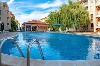 a large blue swimming pool with two buildings at Double Cream Apartment in Tŭnkovo