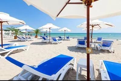 a beach with blue and white chairs and umbrellas at The Red Studio in Burgas City