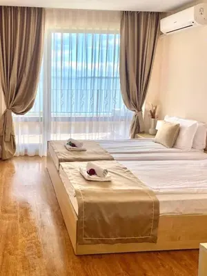 two beds in a bedroom with a large window at Premier Fort Beach Sveti Vlas in Sveti Vlas