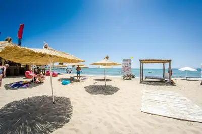 a beach with umbrellas and people on the sand at Premier Fort Beach Sveti Vlas in Sveti Vlas