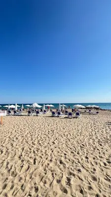 a sandy beach with chairs and umbrellas and the ocean at Fort Noks PRIVILEGE Apartment in Sveti Vlas