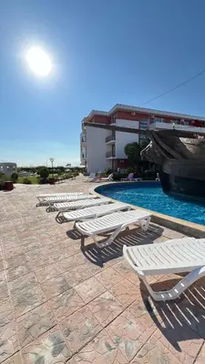 a row of white lounge chairs next to a pool at Fort Noks PRIVILEGE Apartment in Sveti Vlas