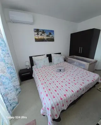 a bedroom with a bed with a red and white comforter at Apartament Primavera Atlantis SPA in Burgas City