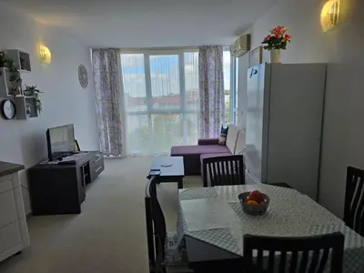 a kitchen and living room with a table and a refrigerator at Apartament Primavera Atlantis SPA in Burgas City