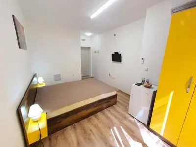 a large room with a bed and a refrigerator at Neptun-Yellow in Primorsko