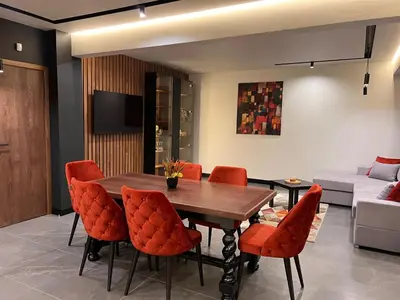 a living room with a wooden table and orange chairs at Maxim Apartment with Free Parking in Varna City