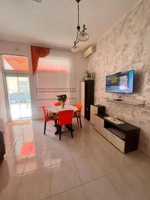 a living room with a table and a tv on a wall at GALI- beach&mud therapy in Pomorie