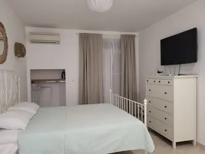 a bedroom with a white bed and a tv on a dresser at Solea Studio in Chernomorets