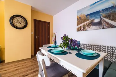 a dining room with a white table and a clock at Luxury apartment with sea view,FREE parking! in Varna City