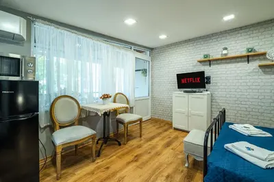 a room with a table and chairs and a kitchen at Cozy Studio in Varna City Center in Varna City