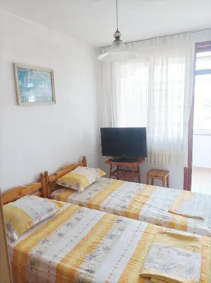 a bedroom with two beds and a television at Rita's - family apartment by the sea in Primorsko