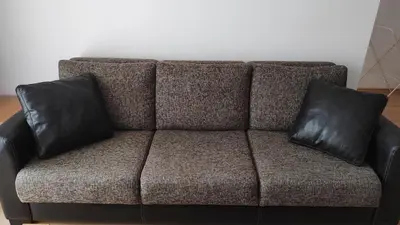 a brown couch with two black pillows on it at Double Cherry Apartment in Sunny Beach