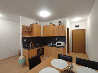 a kitchen with wooden cabinets and a table with chairs at Double Cherry Apartment in Sunny Beach