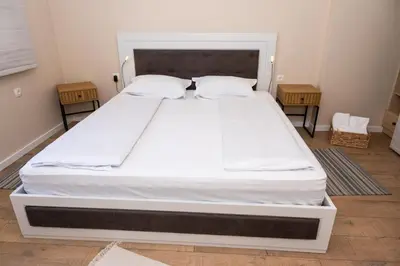 a large white bed in a room with two tables at Apartment Maria in Burgas City