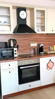 a kitchen with a microwave and a clock on the wall at Студио Черноморски залив Атия Резорт in Chernomorets