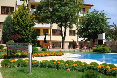 a bench in front of a building with a pool and flowers at Splendid sunny seasons in Byala
