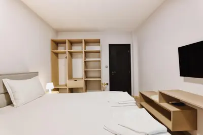 a bedroom with a bed with a desk and a tv at Marina Bay Apartments Kraymorie in Burgas City