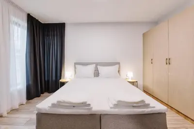 a bedroom with a large white bed with two lamps at Marina Bay Apartments Kraymorie in Burgas City