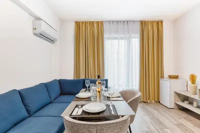 a living room with a blue couch and a table at Marina Bay Apartments Kraymorie in Burgas City