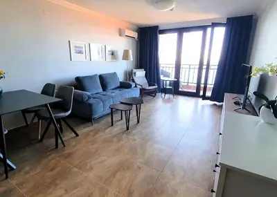 a living room with a blue couch and a table at Panorama Sea View in Sveti Vlas