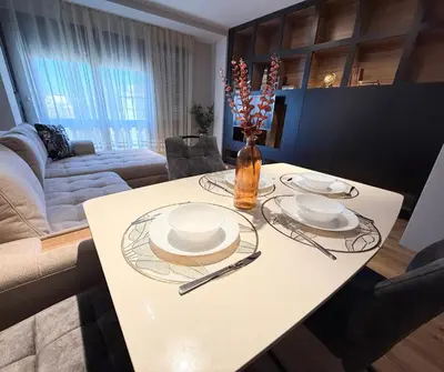 a white table with plates and a vase of flowers on it at Sea Garden luxury appartments in Varna City
