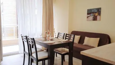 a dining room with a table and chairs and a couch at Апартамент в непосредствена близост до плажа III in Burgas City