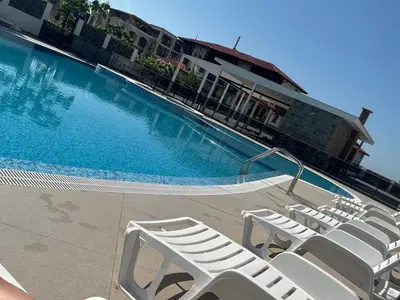 a swimming pool with white lounge chairs in front of a building at Grand Villa Perle in Sveti Vlas