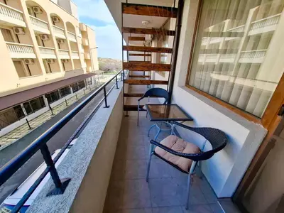 a balcony with chairs and tables on a building at Stamopolu Apartments in Primorsko