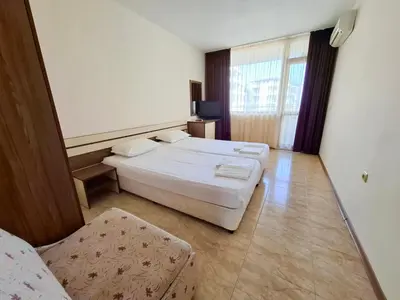 a hotel room with two beds and a chair at Stamopolu Apartments in Primorsko