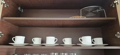 a shelf with white cups and saucers on it at Apartment in complex Sirena! in Sveti Vlas