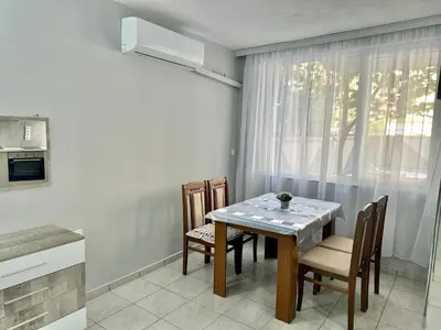 a dining room with a table and chairs and a window at Студио Боряна in Pomorie