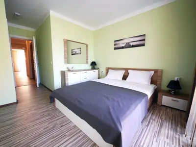 a bedroom with a large bed and green walls at APART-HOTEL Stamopolu Lux с изглед към морето in Primorsko