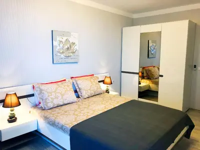 a bedroom with a bed with two lamps and a mirror at APART-HOTEL Stamopolu Lux с изглед към морето in Primorsko