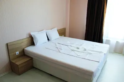 a bedroom with a bed with white sheets and a window at APART-HOTEL Stamopolu Lux с изглед към морето in Primorsko