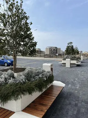 a parking lot with benches and a tree and a car at Lago Mare Apartment in Pomorie