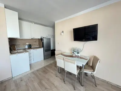 a kitchen and dining room with a table and a television at Pomorian Pearl in Pomorie