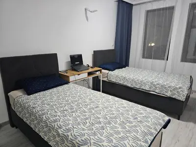a room with two beds and a desk with a laptop at 3 комнатные новые апартаменты у моря in Sveti Vlas