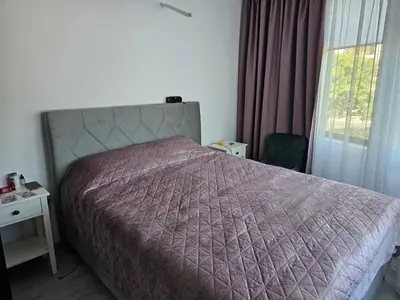 a bedroom with a bed with a purple comforter and a window at 3 комнатные новые апартаменты у моря in Sveti Vlas