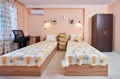 a bedroom with two beds and a desk and a cabinet at АПАРТАМЕНТИ Радина in Pomorie
