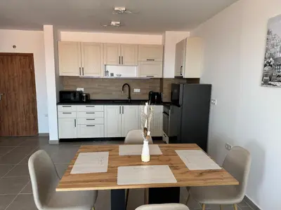 a kitchen with a wooden table with chairs and a refrigerator at Sun Coast by the Sea in Sveti Vlas