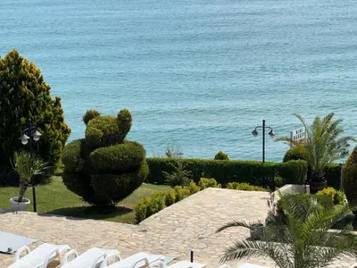 a garden with a cactus and chairs and the ocean at Sun Coast by the Sea in Sveti Vlas
