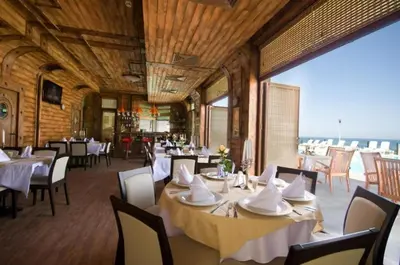 a restaurant with white tables and chairs and a large window at Appart complex - Egrek 2 in Bŭnzareto